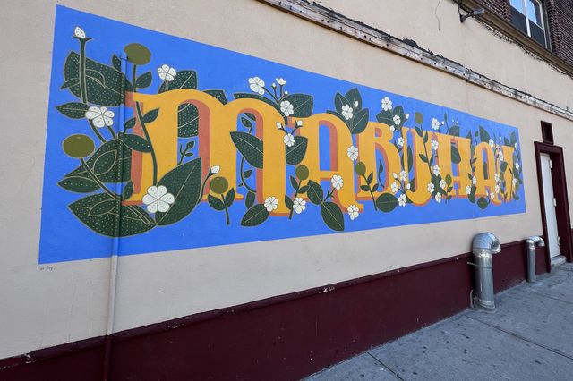 A mural with flowery vines wrapped around the word "Mubahay," an expression that means "Welcome."